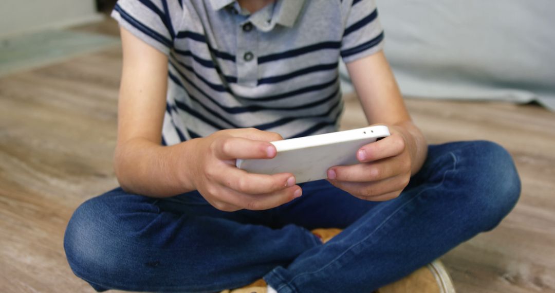 Child Sitting Cross-Legged Playing on Digital Tablet Indoors - Free Images, Stock Photos and Pictures on Pikwizard.com