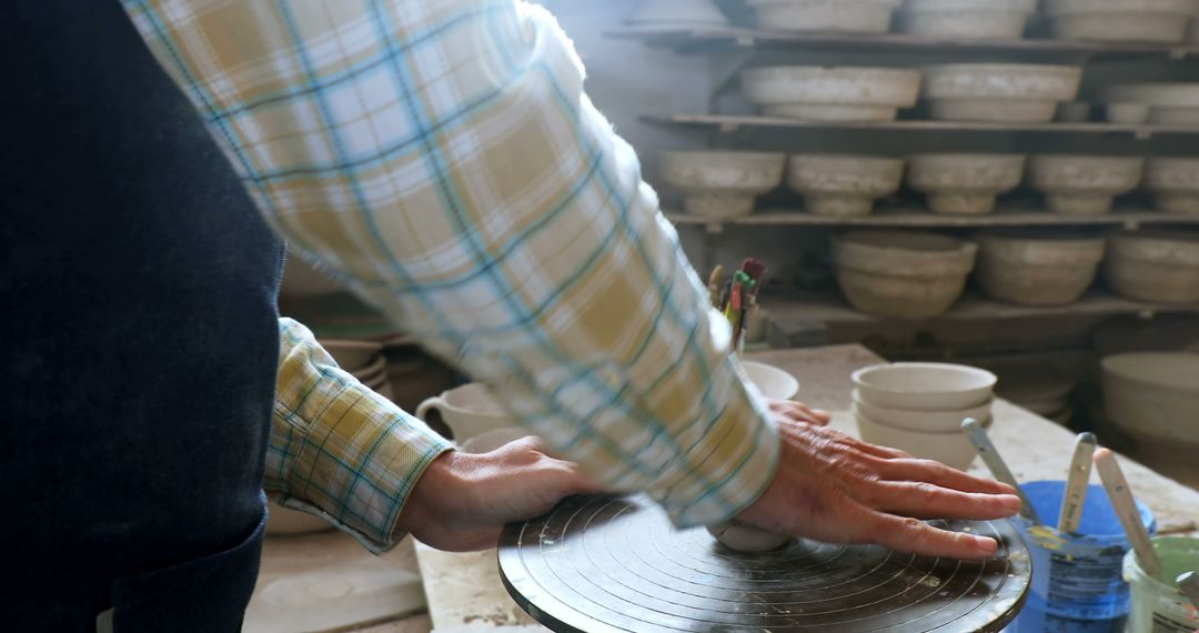 Potter shaping clay on spinning wheel in workshop - Free Images, Stock Photos and Pictures on Pikwizard.com