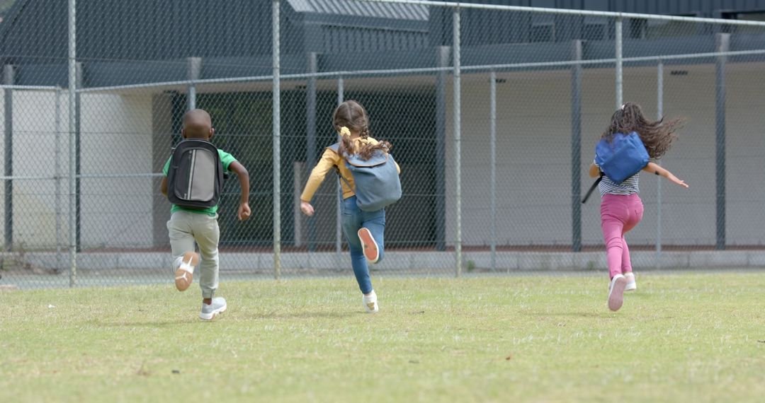 Joyful Children Running Across School Field with Backpacks