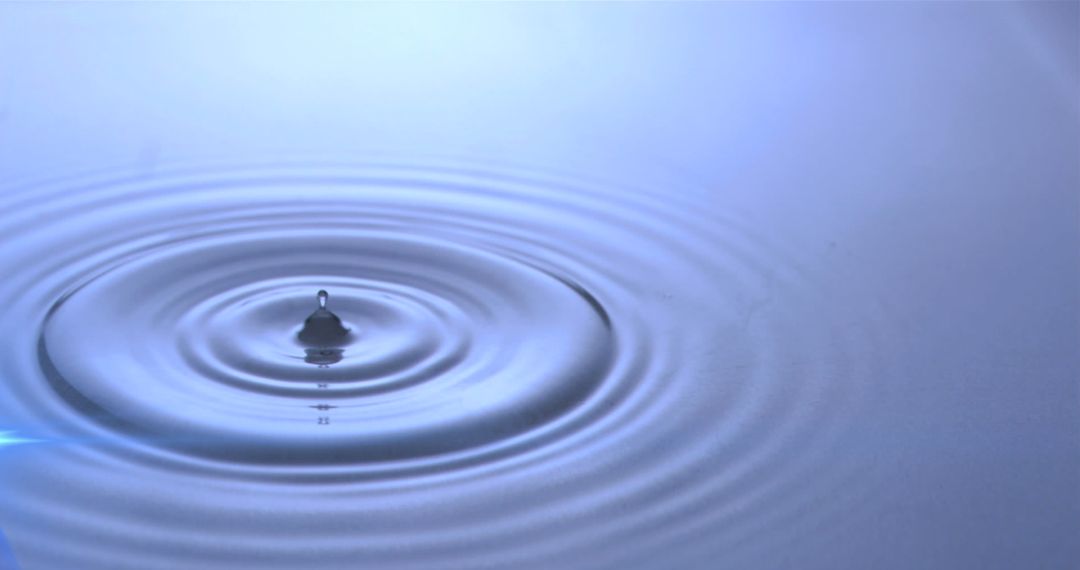 Water Droplets Creating Ripples in Blue Light