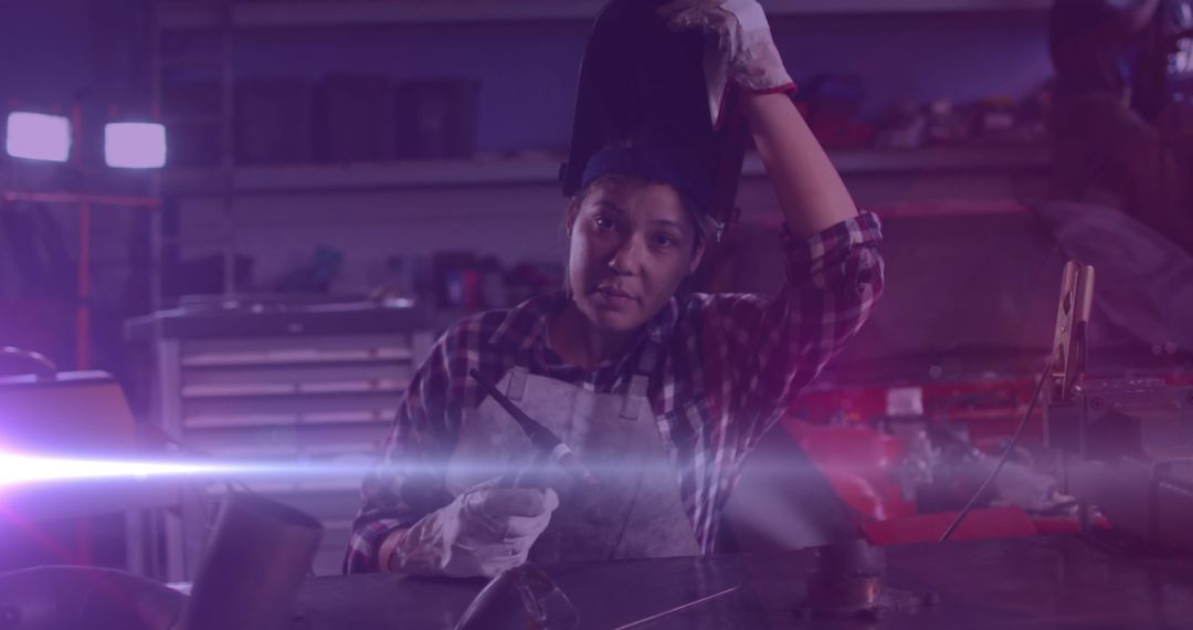 Female Engineer in Workshop Adjusting Welding Helmet