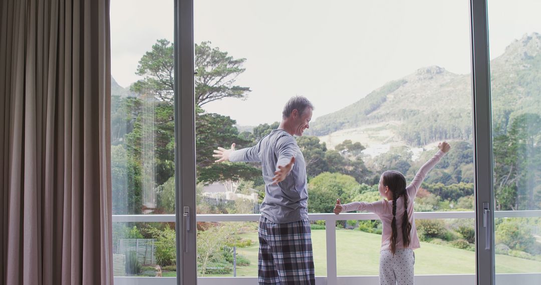 Father and Daughter Stretching by Large Windows with Scenic View - Free Images, Stock Photos and Pictures on Pikwizard.com