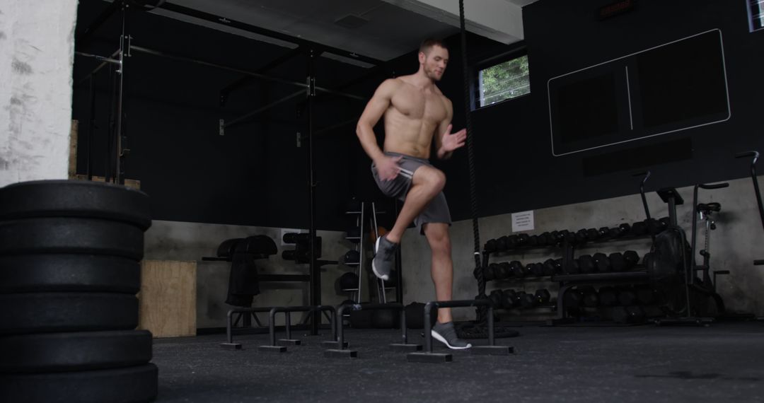 Athletic Shirtless Man Training with Low Hurdles in Gym