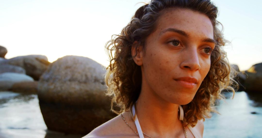 Serene Woman on Rocky Shore at Sunset in Minimalist Scenery
