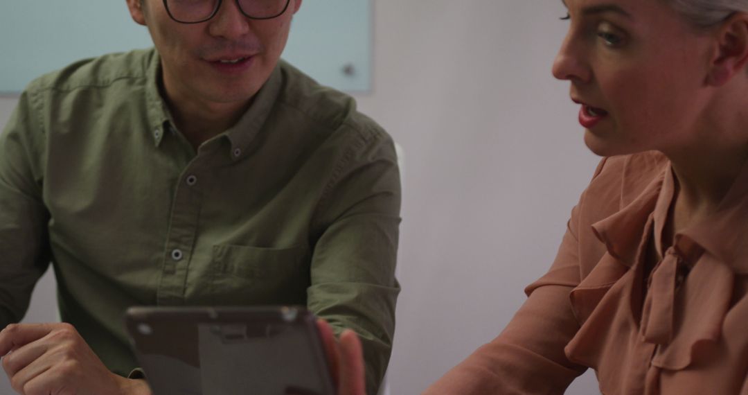 Colleagues Collaborating with Tablet in Office Meeting
