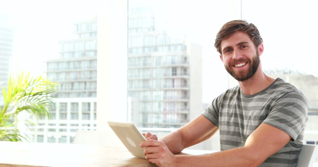 Young Man Smiling with Tablet in Modern Bright Workspace - Free Images, Stock Photos and Pictures on Pikwizard.com