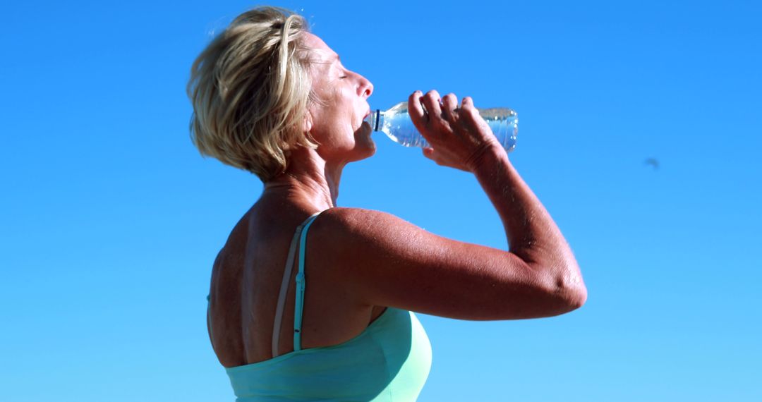 Senior Woman Drinking Water Outdoors Under Clear Blue Sky - Free Images, Stock Photos and Pictures on Pikwizard.com