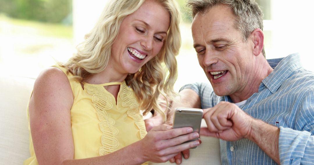 Happy Middle-Aged Couple Enjoying Smartphone Together