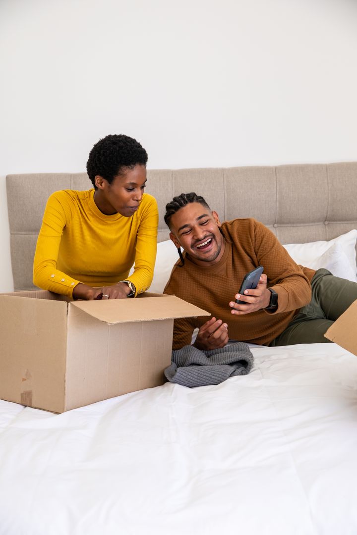 Diverse Couple Unpacking Boxes in Bedroom with Relaxed Atmosphere