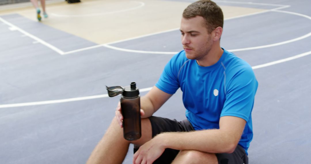 Young athletic man drinking water on basketball court - Free Images, Stock Photos and Pictures on Pikwizard.com