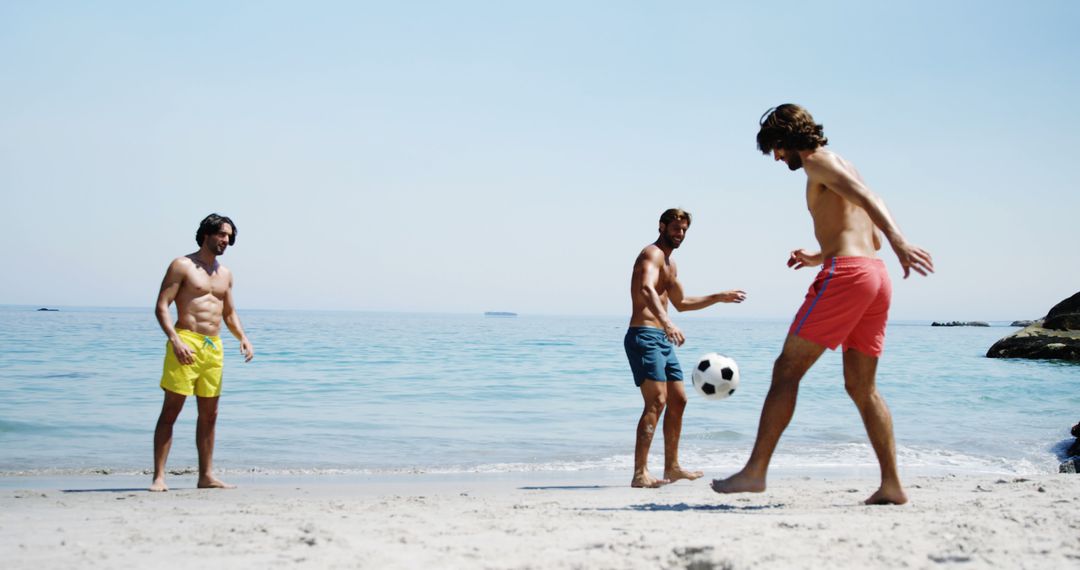 Three Men Playing Soccer on Sunny Sandy Beach