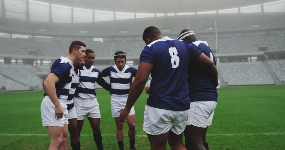 Diverse Rugby Team Huddling on Empty Stadium Pitch