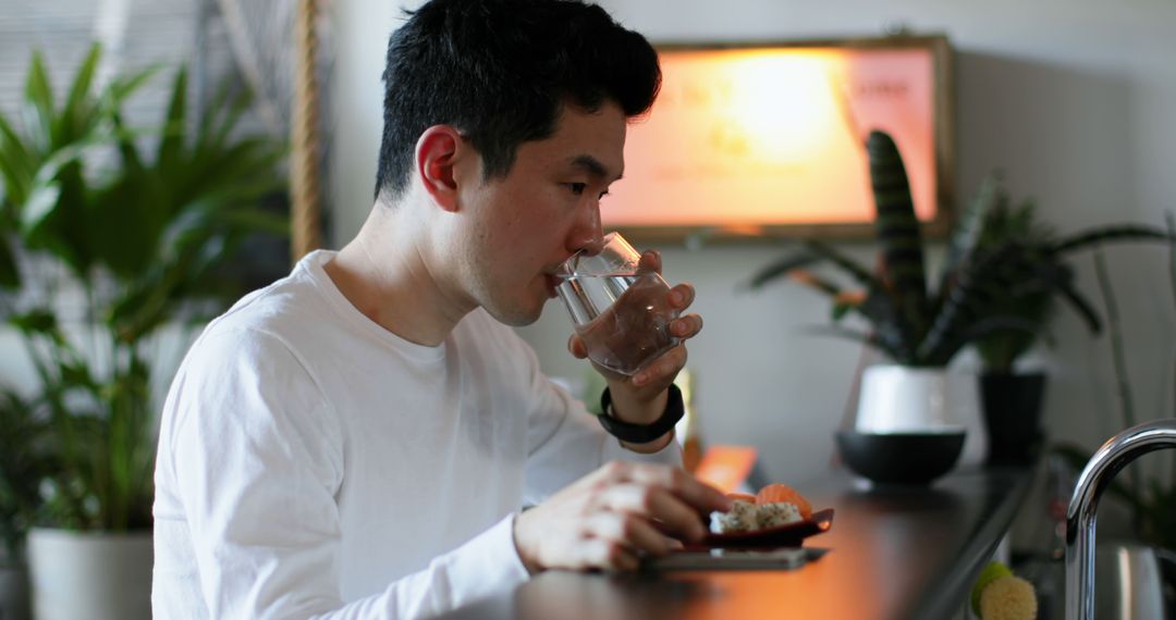 Young Man Drinking Water in Cozy Home Environment - Free Images, Stock Photos and Pictures on Pikwizard.com