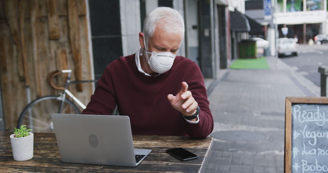 Senior Man Wearing Face Mask Using Laptop at Outdoor Cafe - Free Images, Stock Photos and Pictures on Pikwizard.com