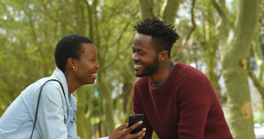 Joyful Couple Sharing Laughs Over Smartphone in Park