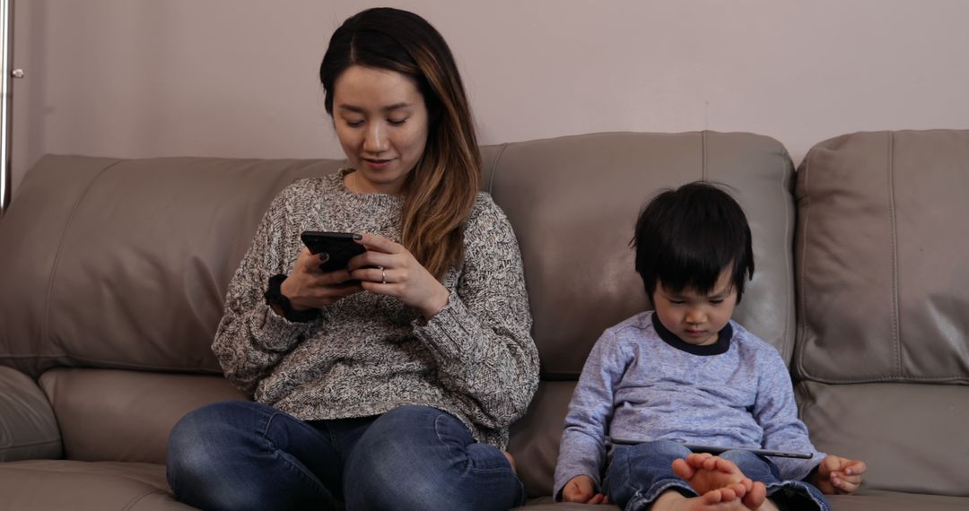 Mother Using Smartphone While Child Sitting on Couch - Free Images, Stock Photos and Pictures on Pikwizard.com