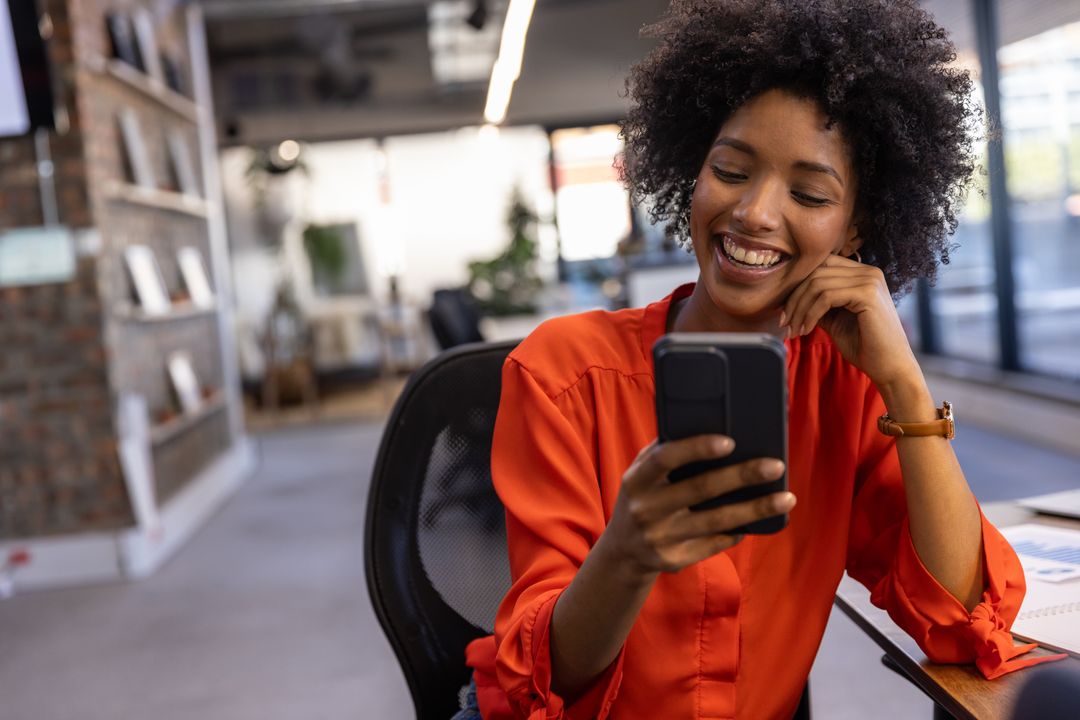 Smiling Professional Using Smartphone at Modern Office Desk