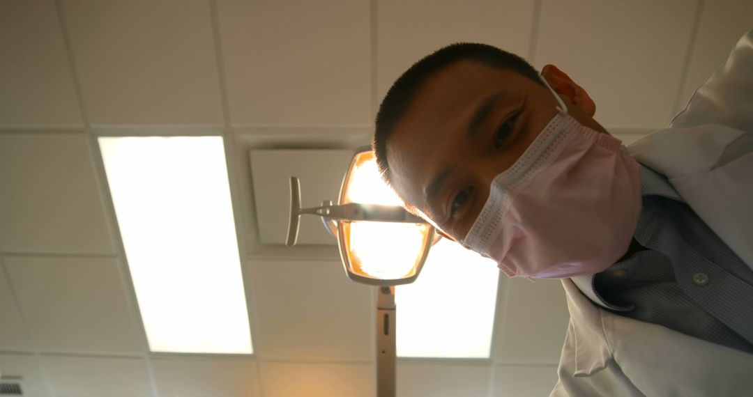 Dentist Wearing Mask Examining Patient from Above - Free Images, Stock Photos and Pictures on Pikwizard.com