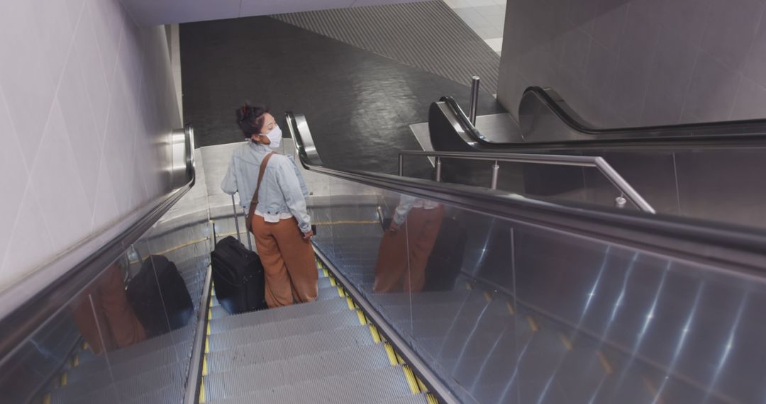 Woman Riding Down Escalator with Luggage in Urban Location - Free Images, Stock Photos and Pictures on Pikwizard.com