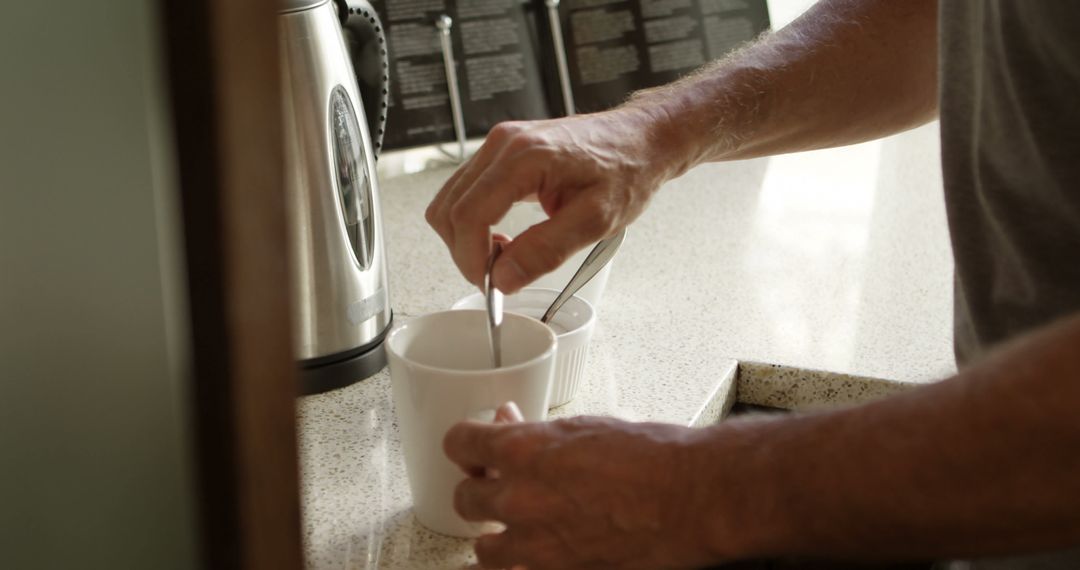 Person Stirring Coffee in Kitchen Near Coffee Maker - Free Images, Stock Photos and Pictures on Pikwizard.com