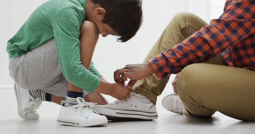 Child Tying Sneakers with Adult's Assistance Indoors - Free Images, Stock Photos and Pictures on Pikwizard.com