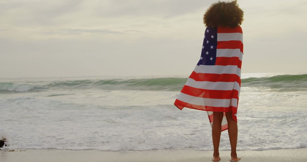 African American Woman Wrapped in Flag Gazing at Ocean