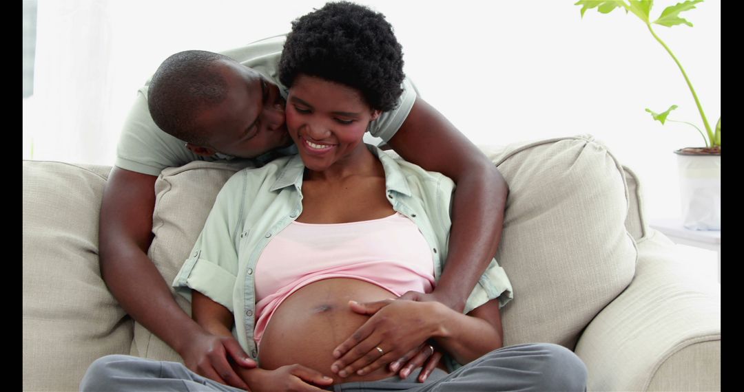 Joyful African American Couple Embracing Pregnancy on Couch - Free Images, Stock Photos and Pictures on Pikwizard.com