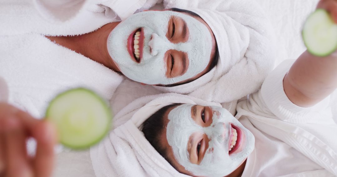 Image of happy asian mother and daughter in robes doing cucumber mask and having fun - Free Images, Stock Photos and Pictures on Pikwizard.com