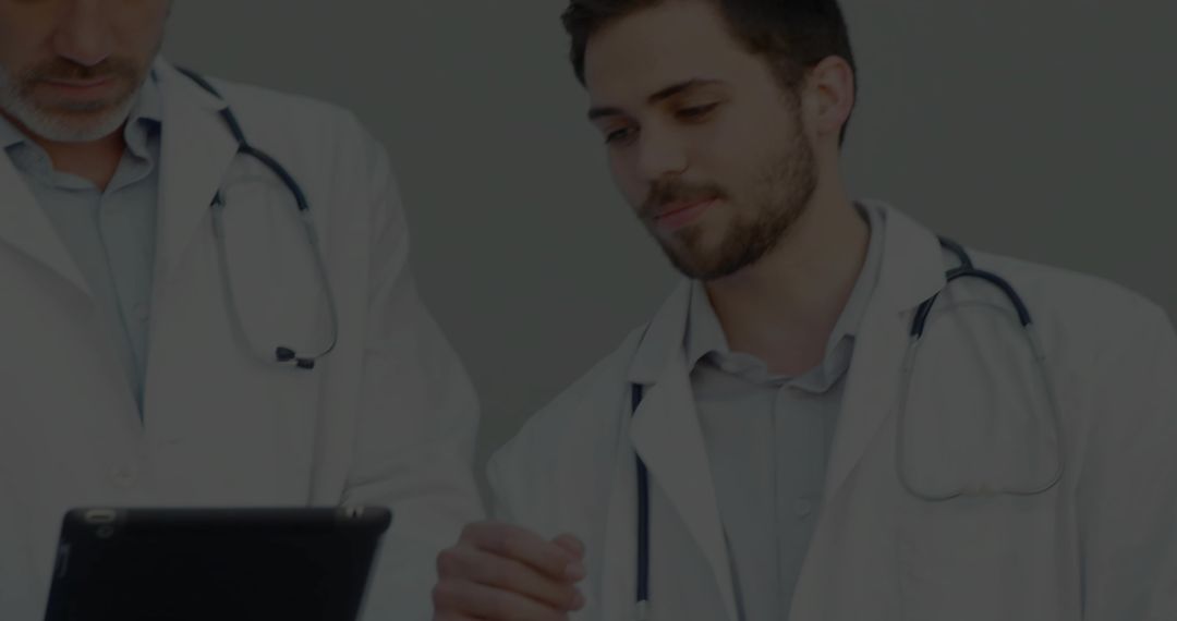 Doctors Collaborating and Reviewing Data on Tablet in Consultation Room