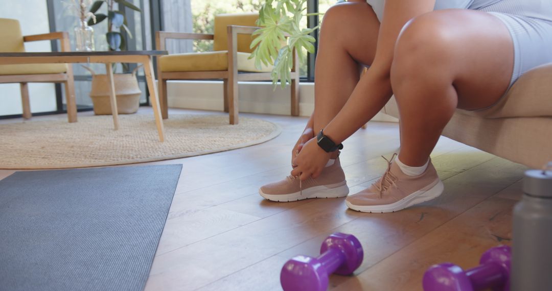 Woman Tying Sneakers for Home Workout with Dumbbells