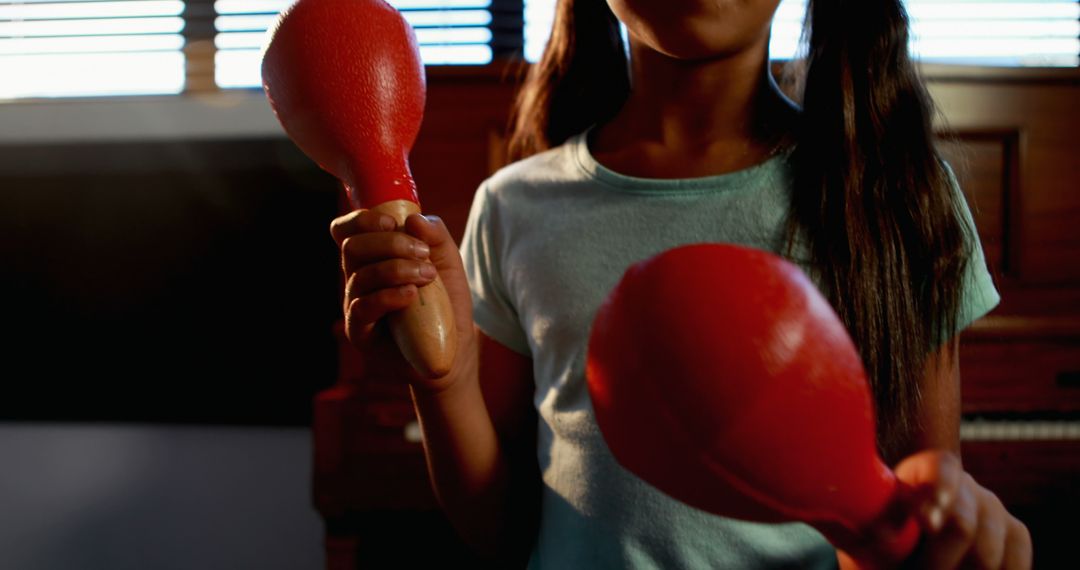 Young girl playing red maracas indoors - Free Images, Stock Photos and Pictures on Pikwizard.com