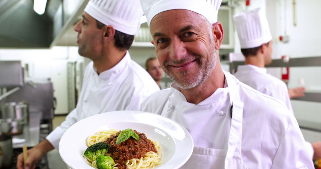 Chef Displaying Spaghetti Dish in Professional Kitchen - Free Images, Stock Photos and Pictures on Pikwizard.com