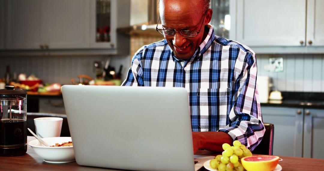 Smiling Elderly Man Working on Laptop in Kitchen with Fresh Fruits and Coffee - Free Images, Stock Photos and Pictures on Pikwizard.com