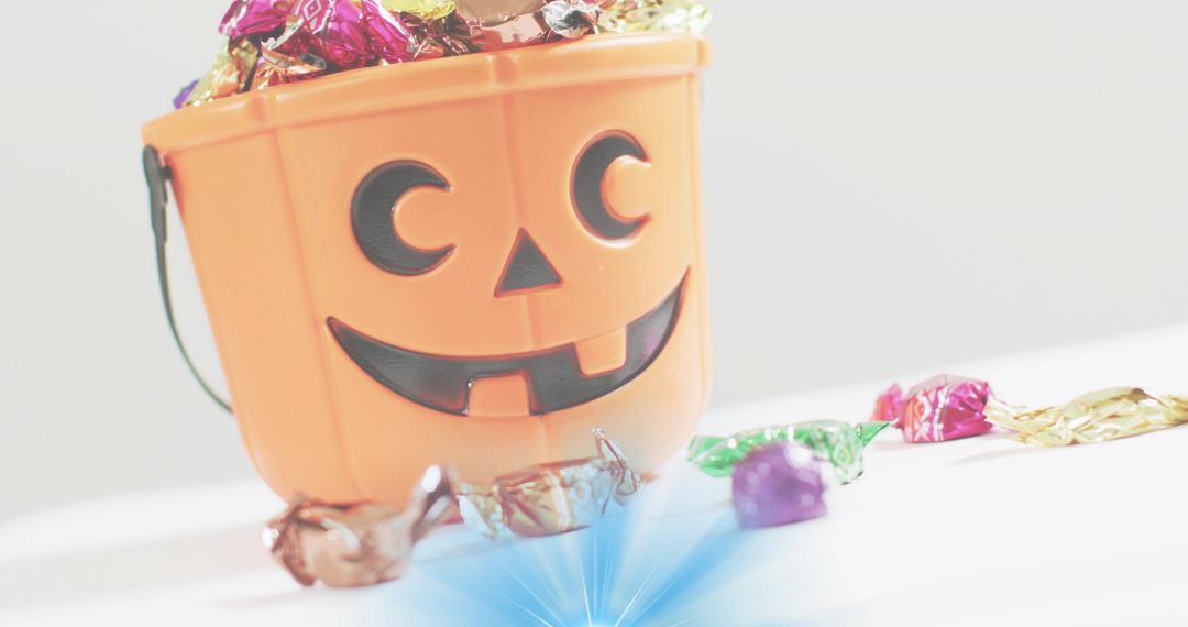 Tilting Halloween Jack-O'-Lantern Candy Bucket Overflowing with Colorful Foil Candies