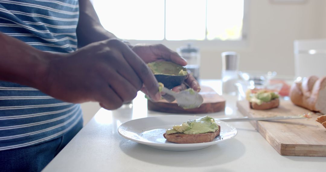 Preparing Avocado Toast in Sunlit Modern Kitchen - Free Images, Stock Photos and Pictures on Pikwizard.com