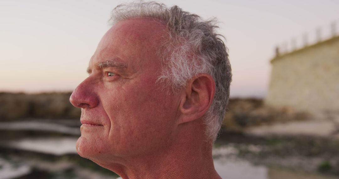 Senior Man Reflecting at Seaside During Sunset
