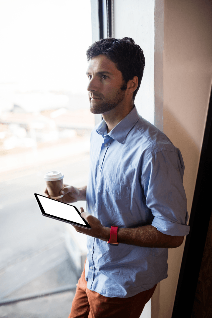 Thoughtful Man with Tablet and Coffee by Large Transparent Window