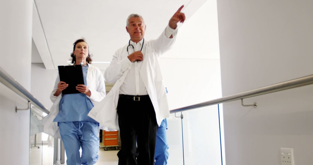 Senior Doctor Leading Team in Hospital Hallway - Free Images, Stock Photos and Pictures on Pikwizard.com