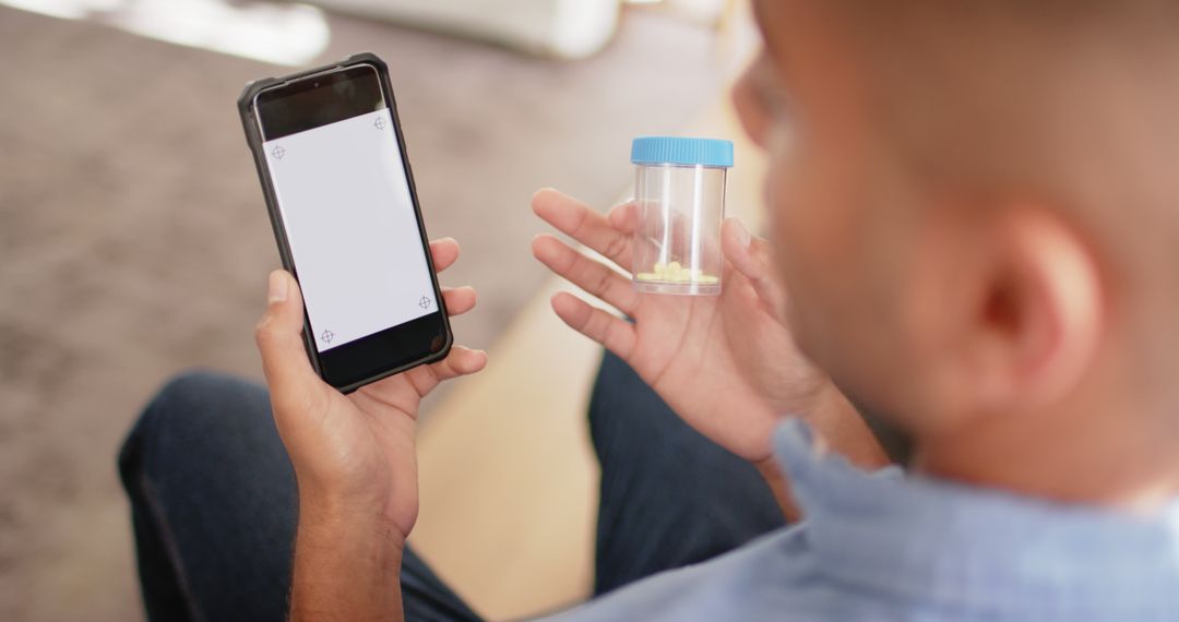 Man Holding Mobile Phone and Medication Container - Free Images, Stock Photos and Pictures on Pikwizard.com