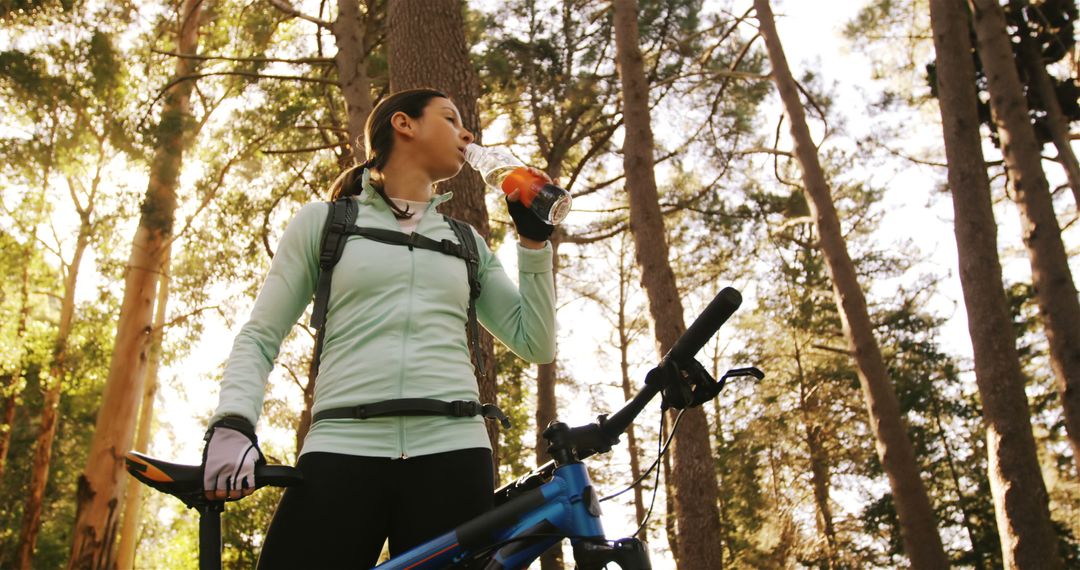 Cyclist taking break in lush forest and drinking a refreshing beverage - Free Images, Stock Photos and Pictures on Pikwizard.com