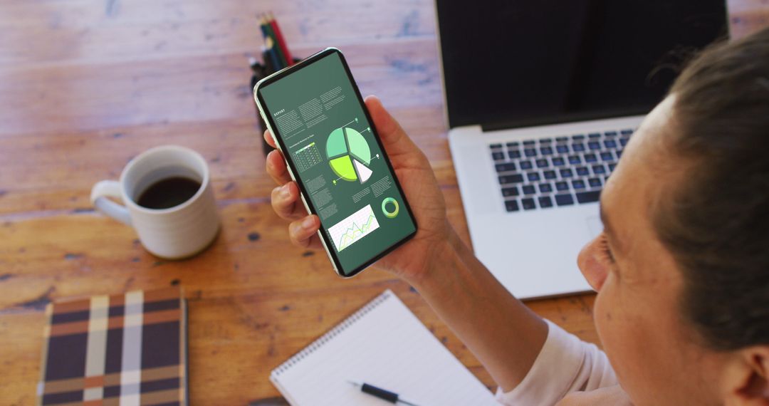 Woman Analyzing Statistics on Smartphone at Desk