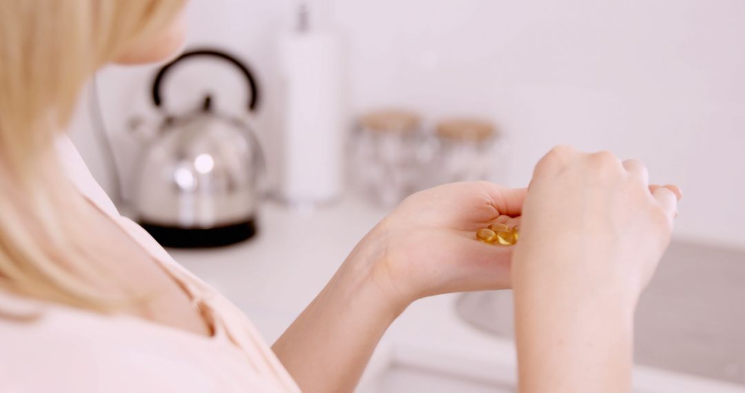 Woman holding pills in the kitchen - Free Images, Stock Photos and Pictures on Pikwizard.com