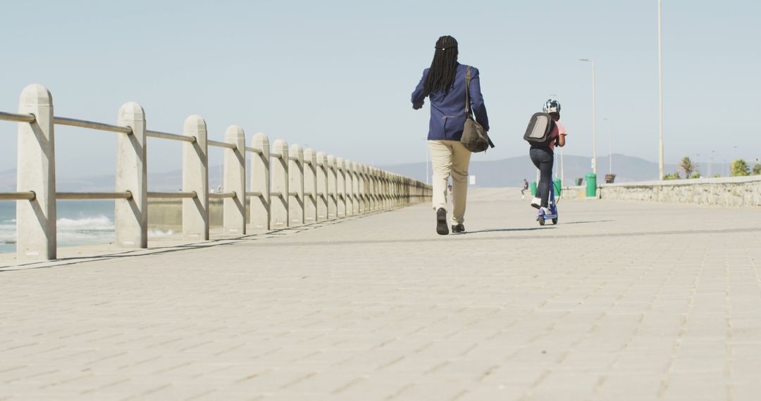 Father Walking with Child on Scooter by Seaside Promenade - Free Images, Stock Photos and Pictures on Pikwizard.com