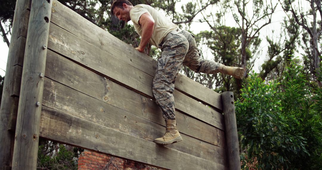 Male Soldier Climbing Over Wooden Obstacle Wall During Military Training - Free Images, Stock Photos and Pictures on Pikwizard.com