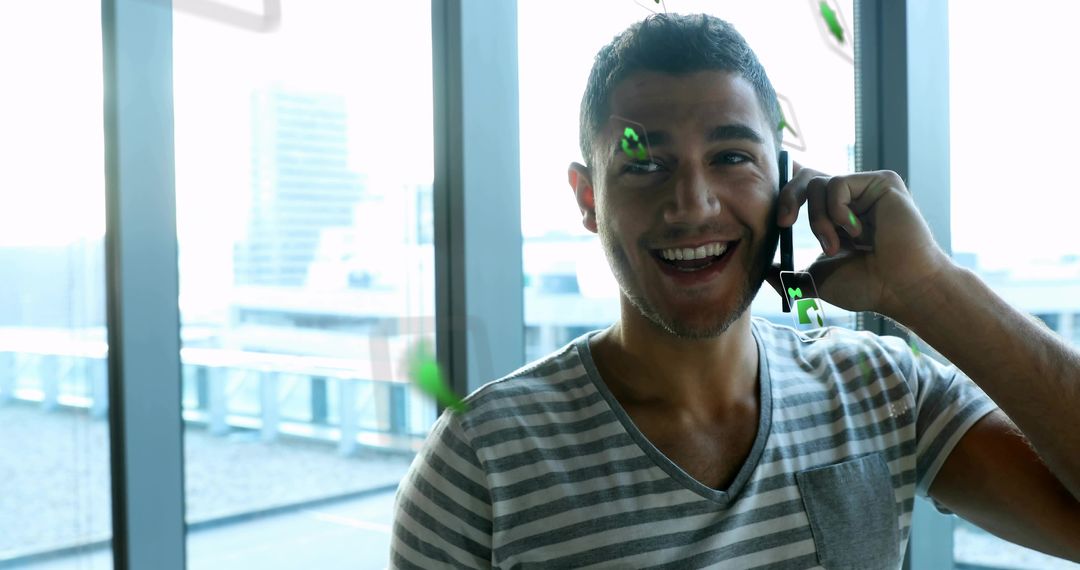 Smiling Man in Casual Tee Calling Near Office Windows with Graphics