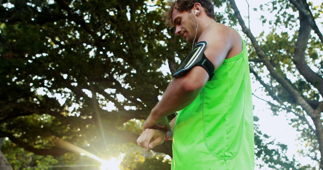 Man in Bright Green Tank Top Adjusting Smartwatch During Outdoor Workout - Free Images, Stock Photos and Pictures on Pikwizard.com