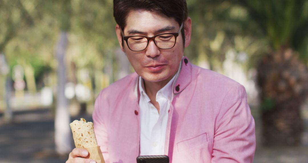 Man in Pink Blazer Eating Wrap and Using Smartphone Outdoors - Free Images, Stock Photos and Pictures on Pikwizard.com