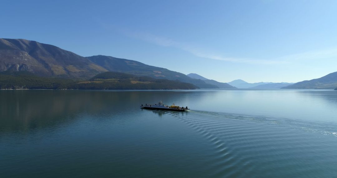 Peaceful Ferry Crossing Lake with Mountain Landscape Under Clear Sky - Free Images, Stock Photos and Pictures on Pikwizard.com