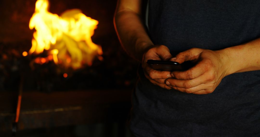 Person with Dirty Hands Using Smartphone in Front of Fire - Free Images, Stock Photos and Pictures on Pikwizard.com