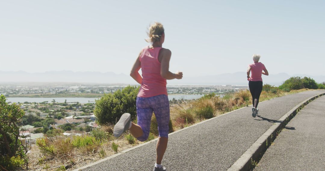 Two Women Jogging On Scenic Trail Overlooking Town - Free Images, Stock Photos and Pictures on Pikwizard.com